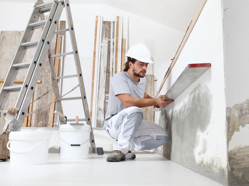 About Us - Trident Restoration Inc. - Crew member working on restoring a water damaged wall.