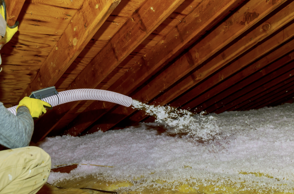 Blown-In Insulation | Photo of a man filling an attic with blown-in insulation.