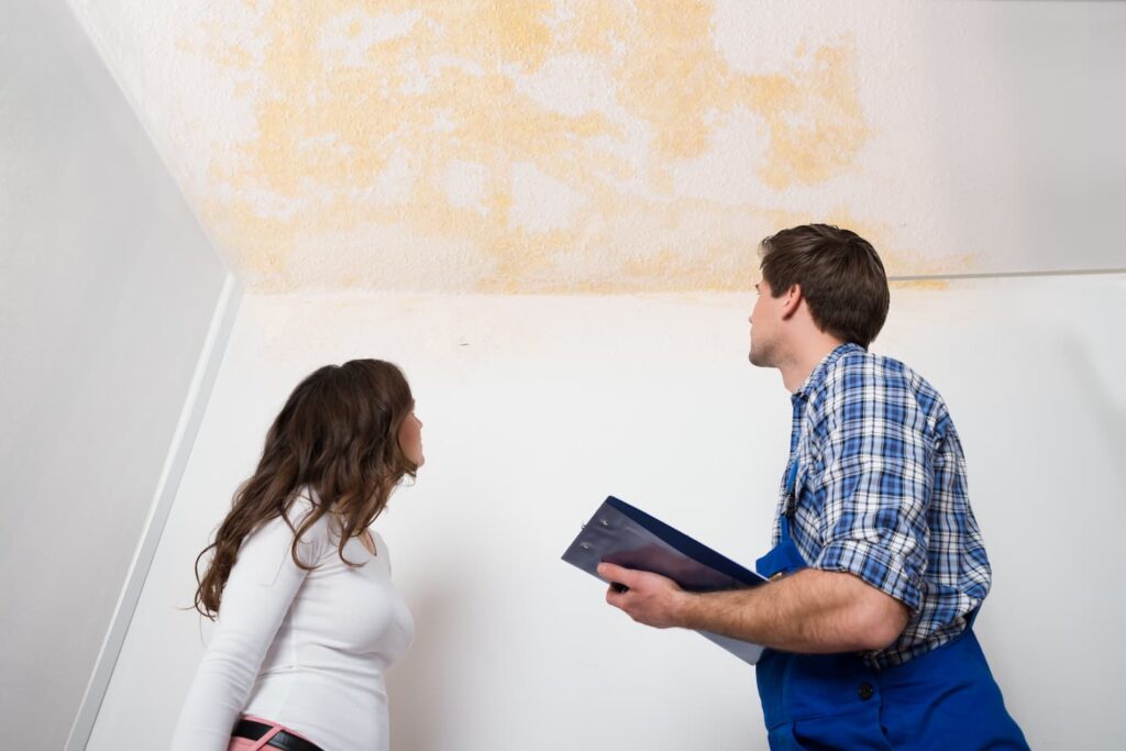 What is a master water restorer certification? A water damage restoration professional assess water damage to a ceiling in a woman's home.